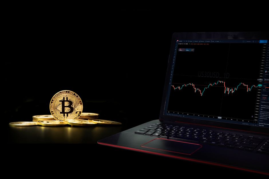 Golden bitcoin coins next to a laptop displaying a trading graph, symbolizing digital currency investment to illustrate crypto prop firm trading 2026