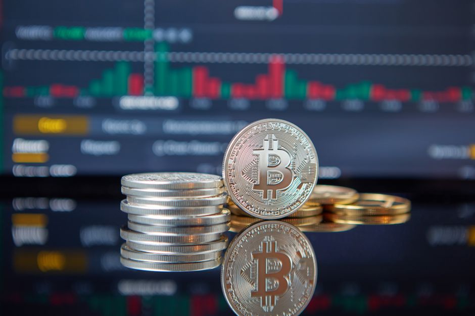 Stack of Bitcoin coins in front of a stock market graph, reflecting cryptocurrency trends to illustrate How Much Capital Can You Get From a Prop Firm